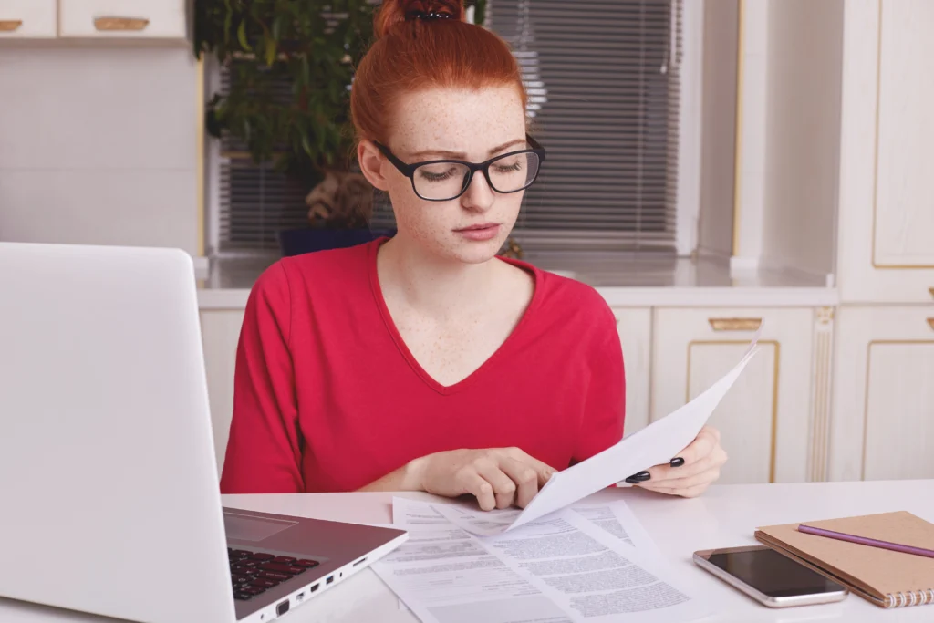 Young woman checking her final university project on laptop to avoid plagiarism (TFG)