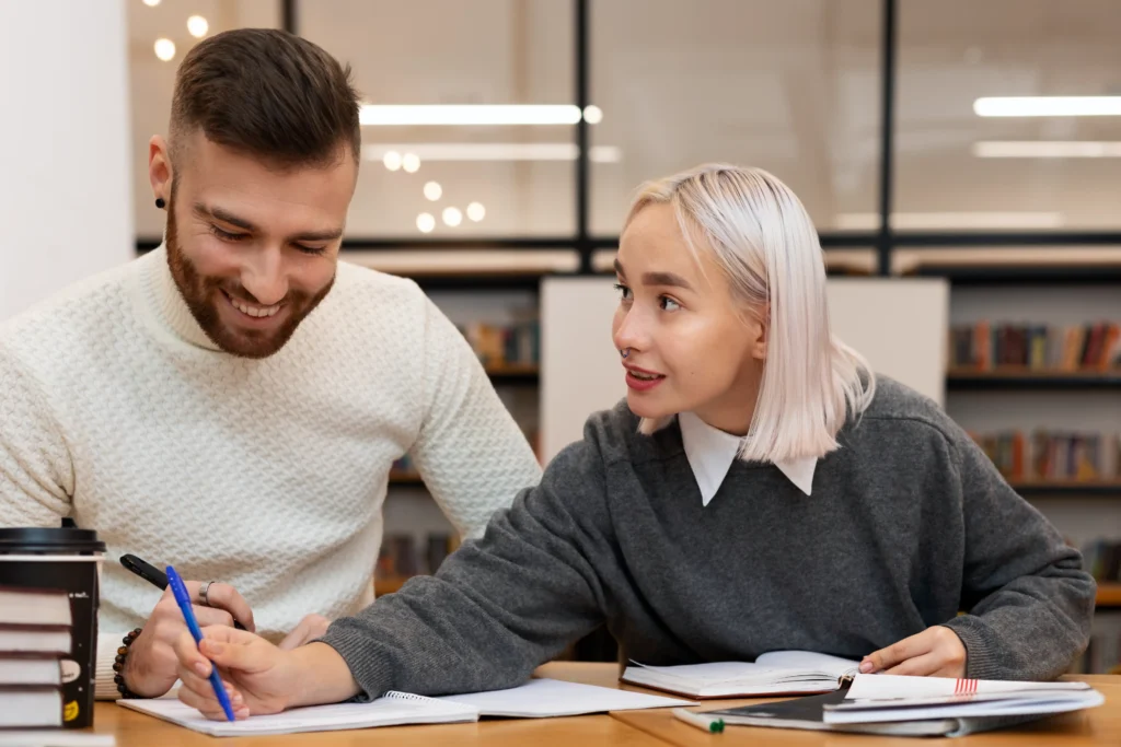 Estudiante recibiendo mentoría sobre su TFM en una biblioteca