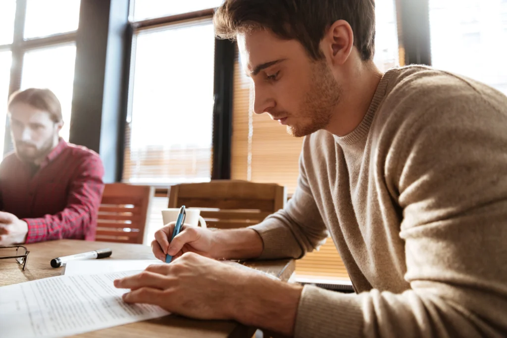 Estudiante revisando y corrigiendo su TFG con un bolígrafo sobre un documento impreso